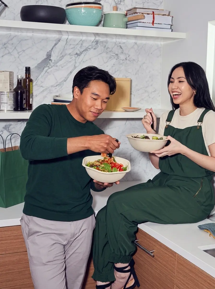 Biccy and Praew, the bohly. founders, sharing bowls in a kitchen
